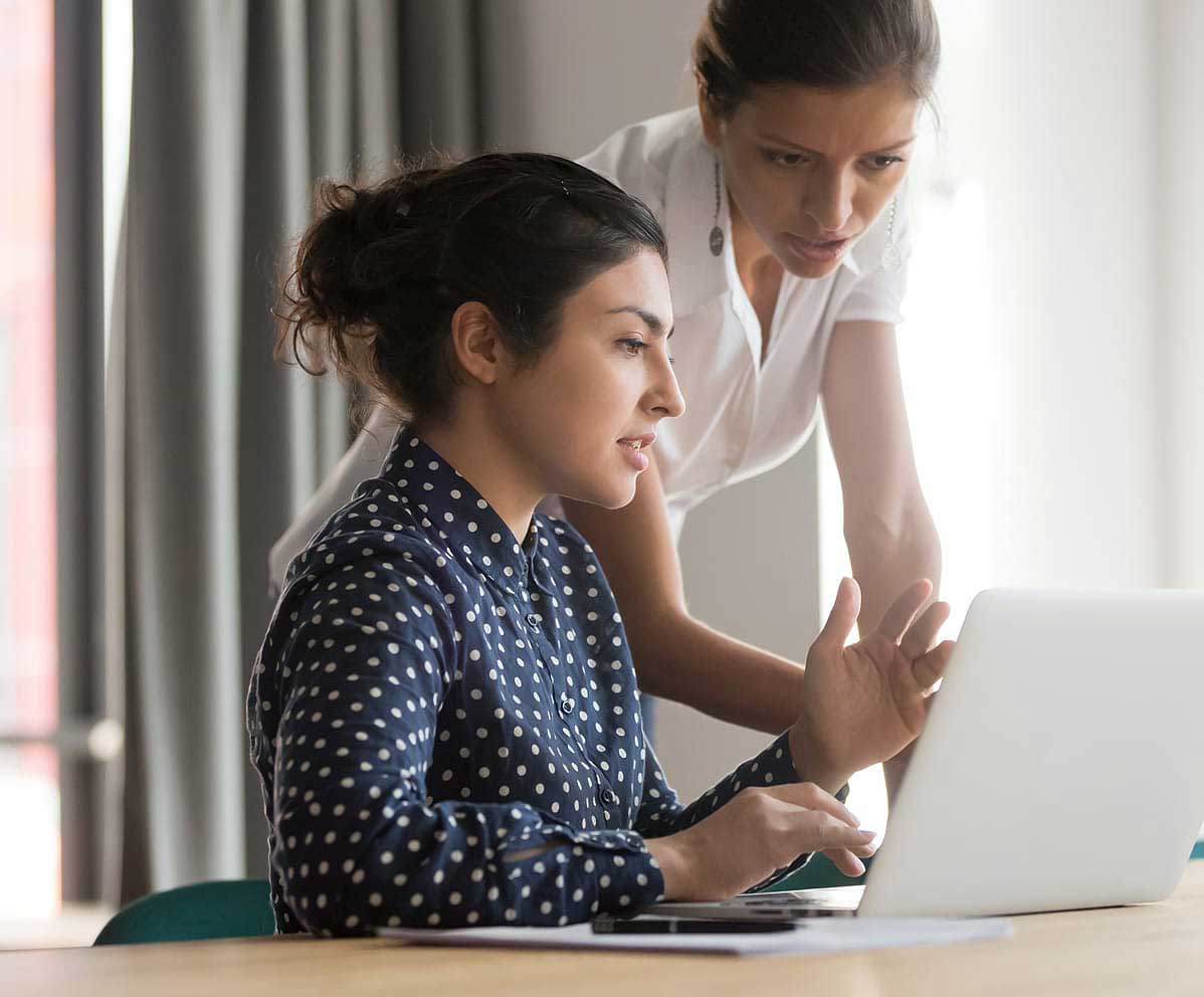 two women looking at laptop in office